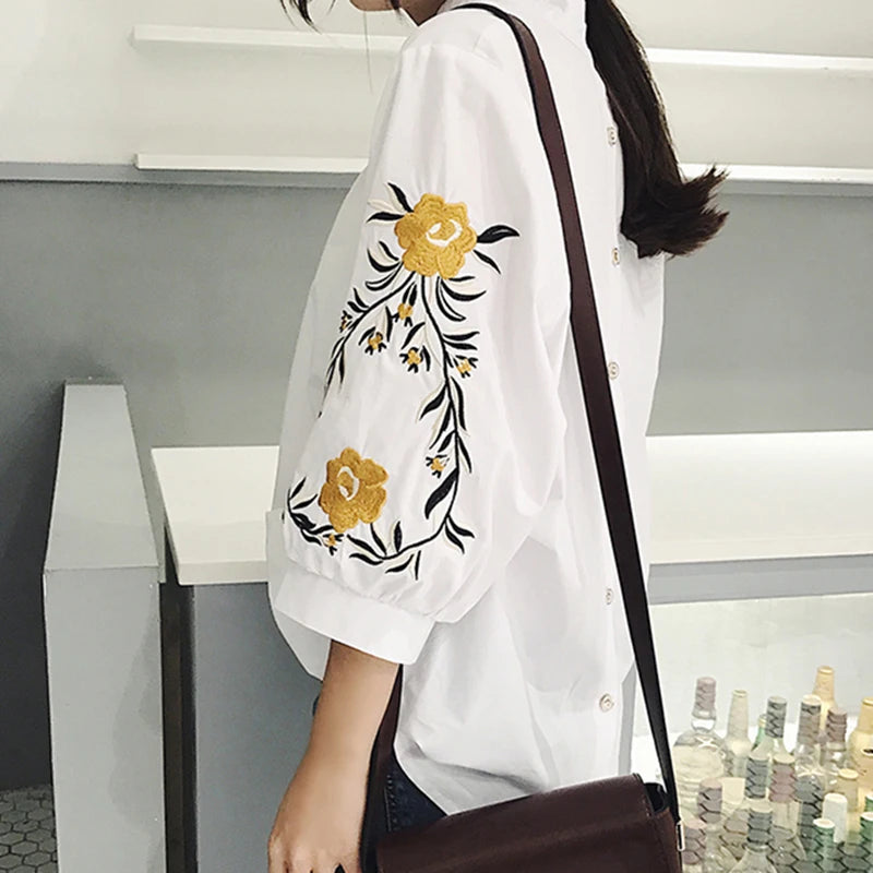 Estilo casual com toque delicado! Blusa feminina branca com listras, bordado floral e decote V elegante. Modelagem soltinha com manga 3/4, perfeita para looks leves e modernos.
