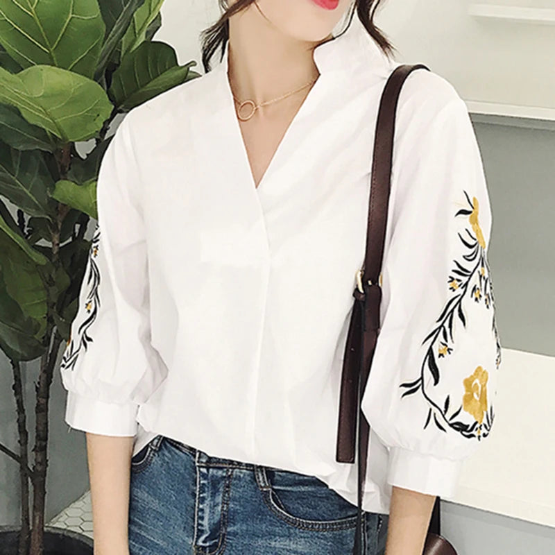 Estilo casual com toque delicado! Blusa feminina branca com listras, bordado floral e decote V elegante. Modelagem soltinha com manga 3/4, perfeita para looks leves e modernos.