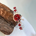 elógio feminino sofisticado, com caixa redonda em liga metálica, mostrador clássico com números árabes e ponteiros em formato de folha. Pulseira delicada com detalhes em strass, combinando charme e estilo